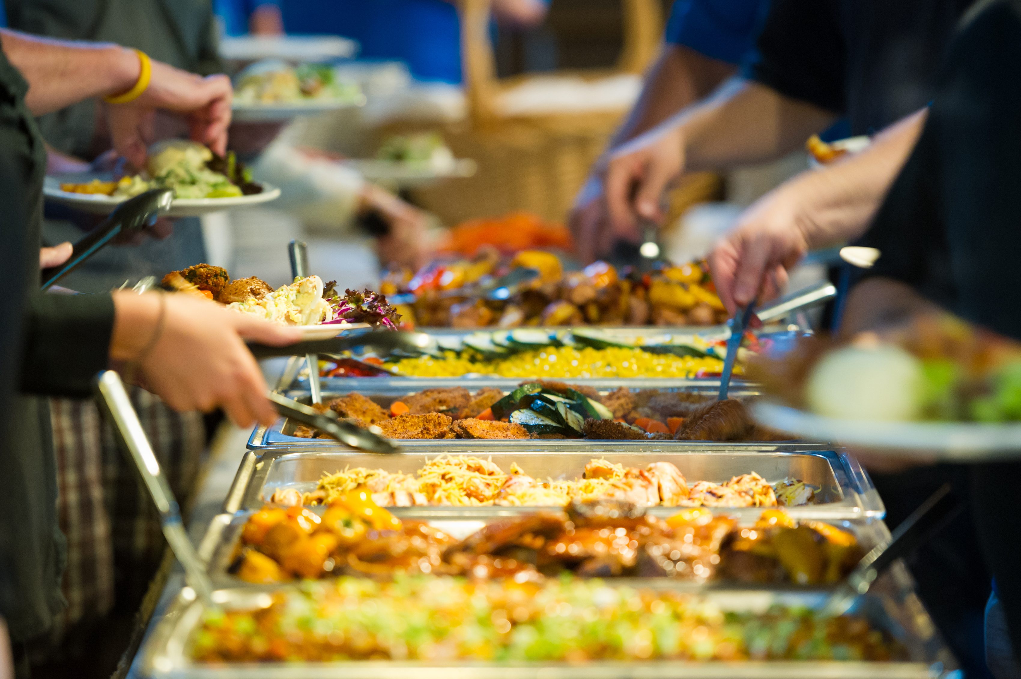 أناس يتناولون الطعام من بوفيه/ Istock
