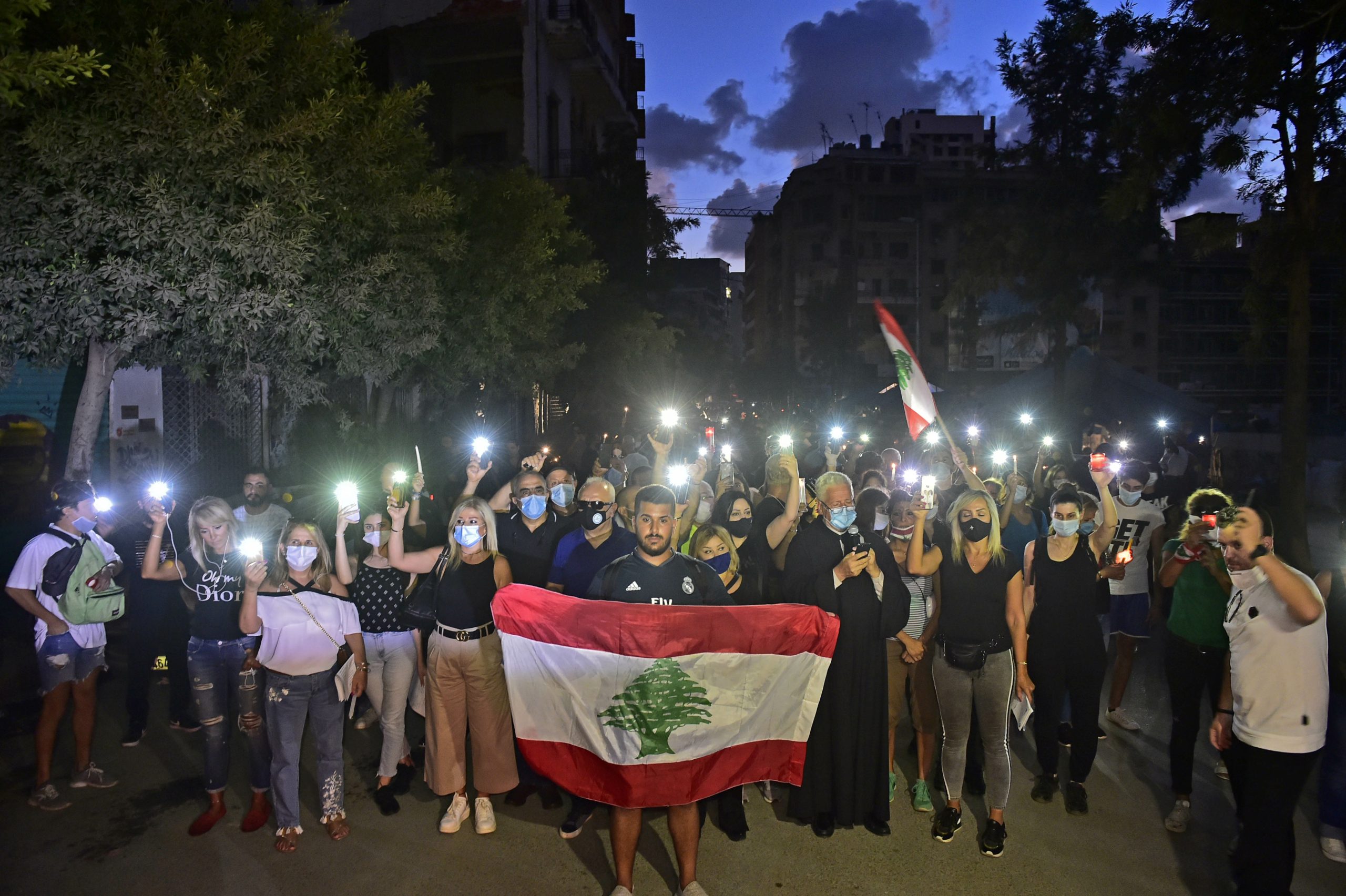 بالشموع وعلم لبنان.. العشرات يتجمعون في محيط انفجار مرفأ بيروت