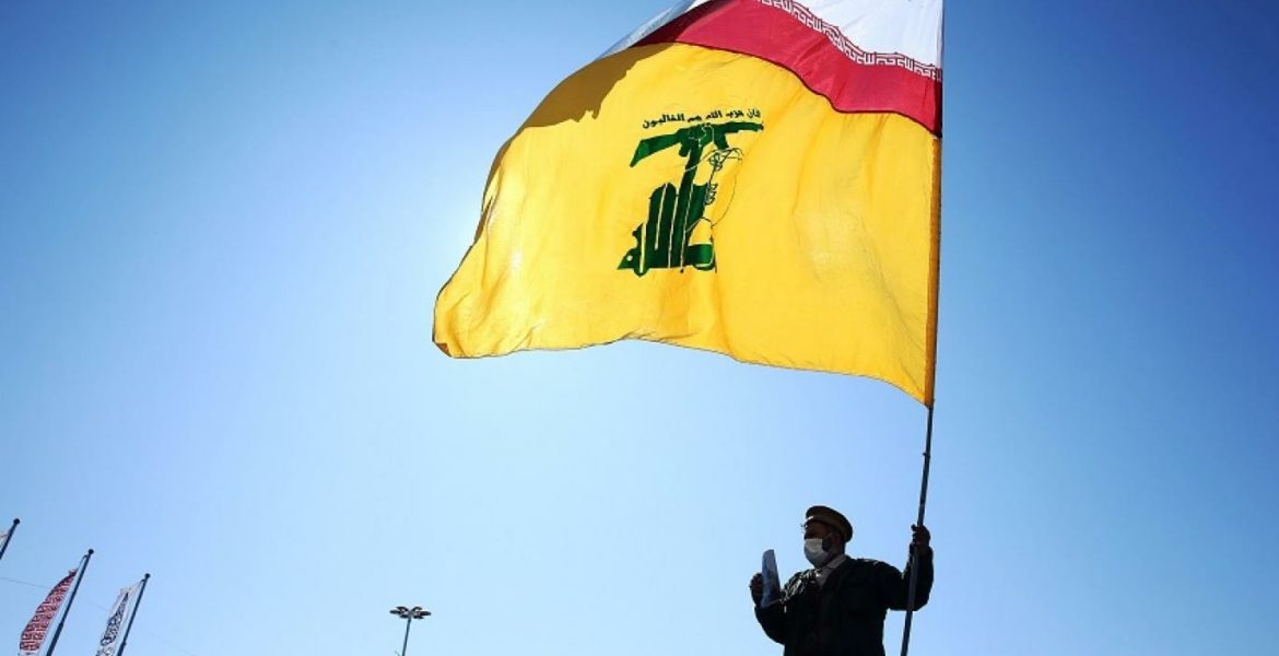 إيراني في طهران يحمل علم "حزب الله" يعلوه العلم الإيراني في الذكرى الـ41 للثورة الإيرانية - رويترز