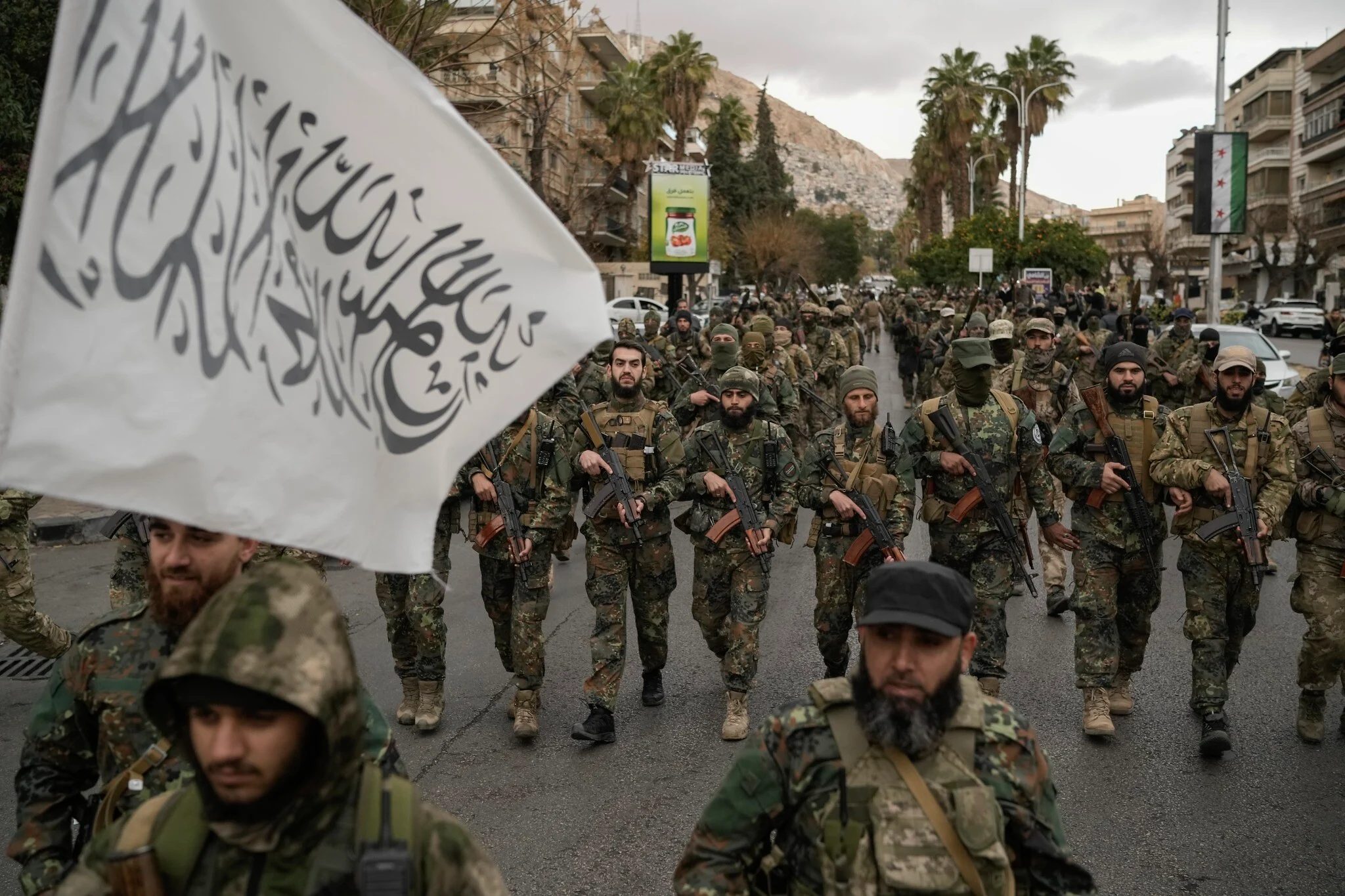 أفراد من القوات المسلحة الجديدة في سوريا، وهم مقاتلون سابقون أطاحوا بنظام الأسد ويخدمون الآن في الحكومة السورية الجديدة، خلال عرض عسكري في وسط مدينة دمشق، سوريا، 27 ديسمبر/كانون الأول 2024 - Getty